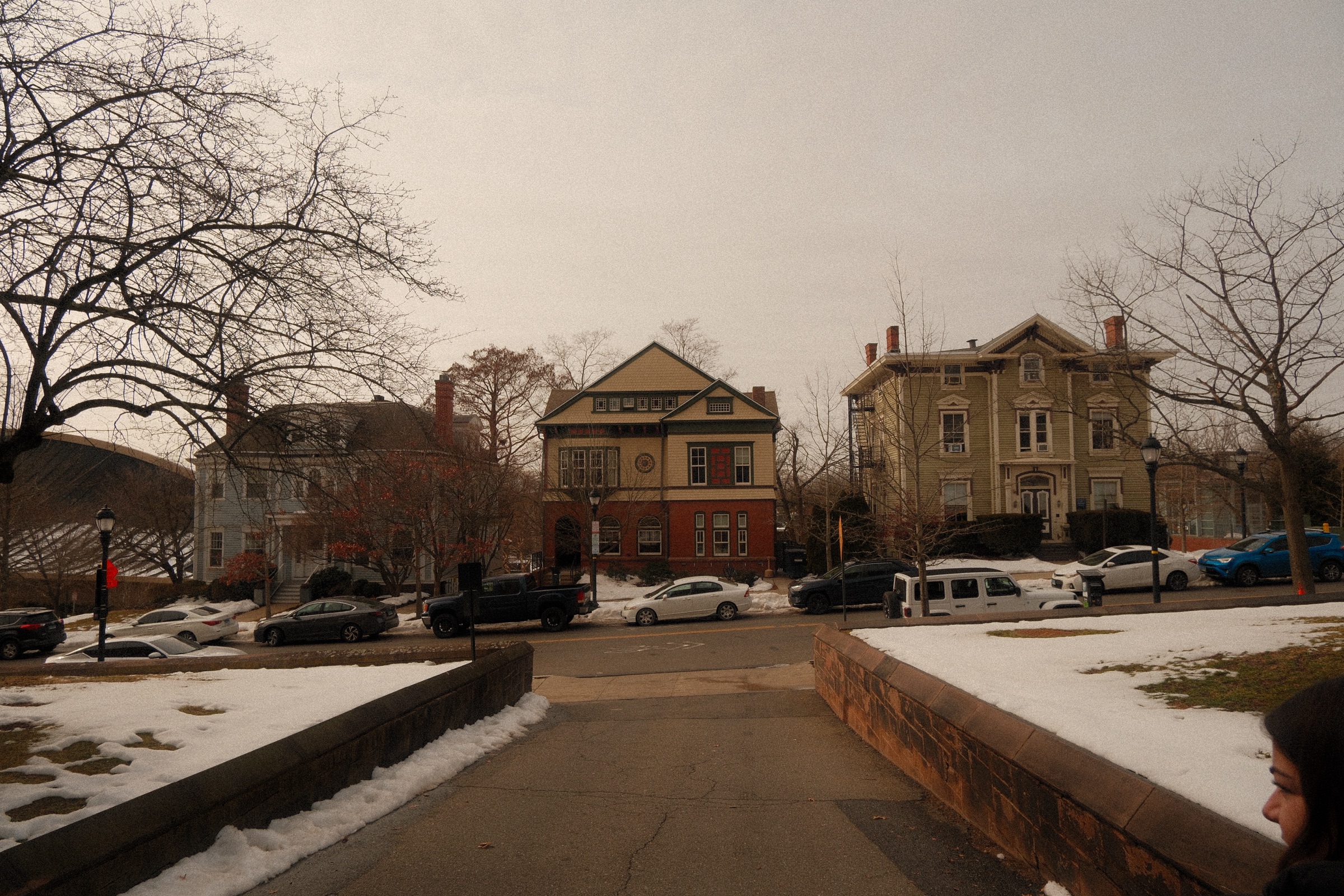 A New England town green in winter, clapboard and brick buildings under a flat overcast sky
